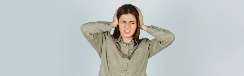 A woman holding her head with both hands, appearing to be in pain or discomfort.